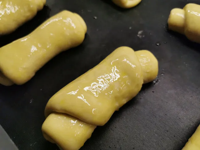 Perfekt geformte, goldbraune italienische Panini vor dem Backen, bereit für den Ofen