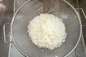 Perfekt gekochter Reis wird in einem feinen Sieb abgegossen und abgetropft