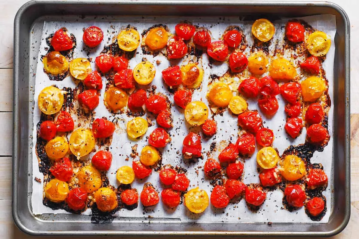 Perfekt geröstete Kirschtomaten, leicht karamellisiert, auf einem Backblech nach dem Garen im Ofen.