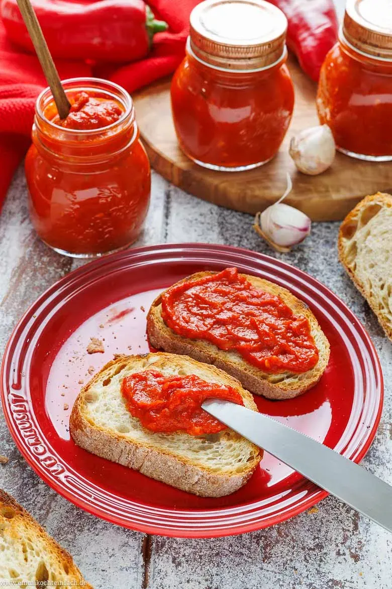 Pikantes Ajvar als Brotaufstrich auf einem Holzbrett, perfekt für eine herzhafte Brotzeit