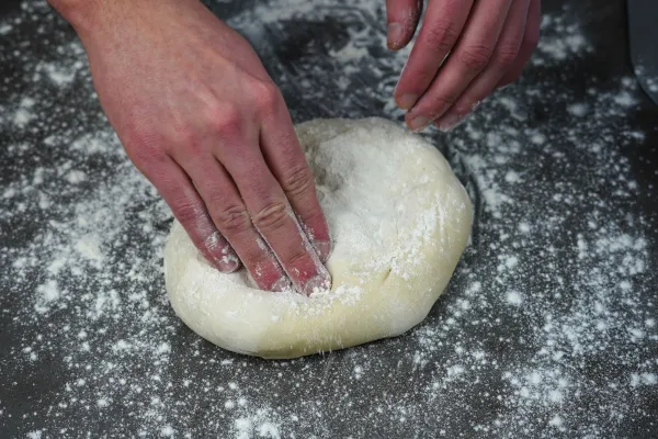 Pizzateig mit den Fingerspitzen vergrößern