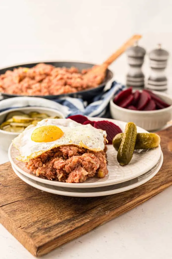 Portion Labskaus mit Spiegelei, garniert mit eingelegten Rote Bete und Gurken