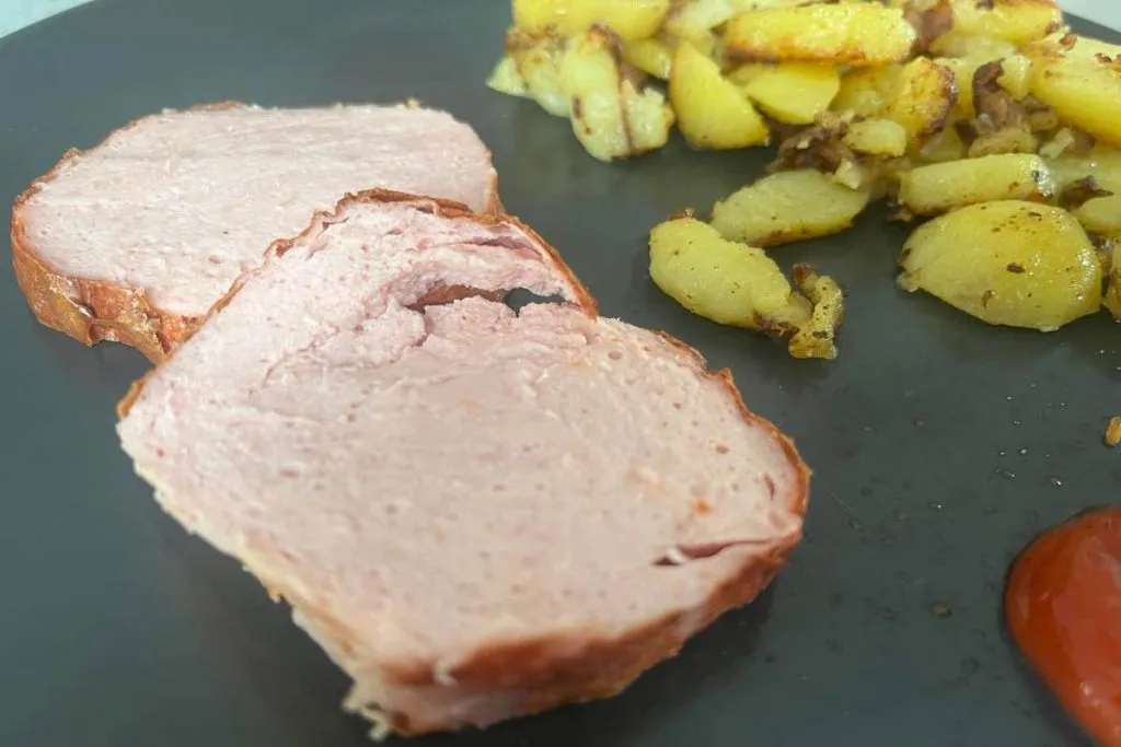 Portion Leberkäse mit Bratkartoffeln und Spiegelei auf einem Teller