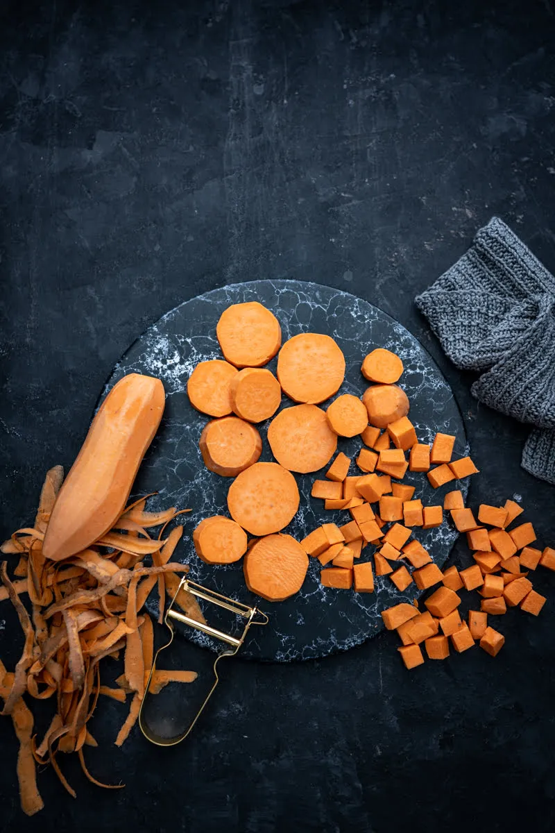 Portion Süßkartoffel-Erdnusscurry in einer Schale, garniert mit frischen Kräutern