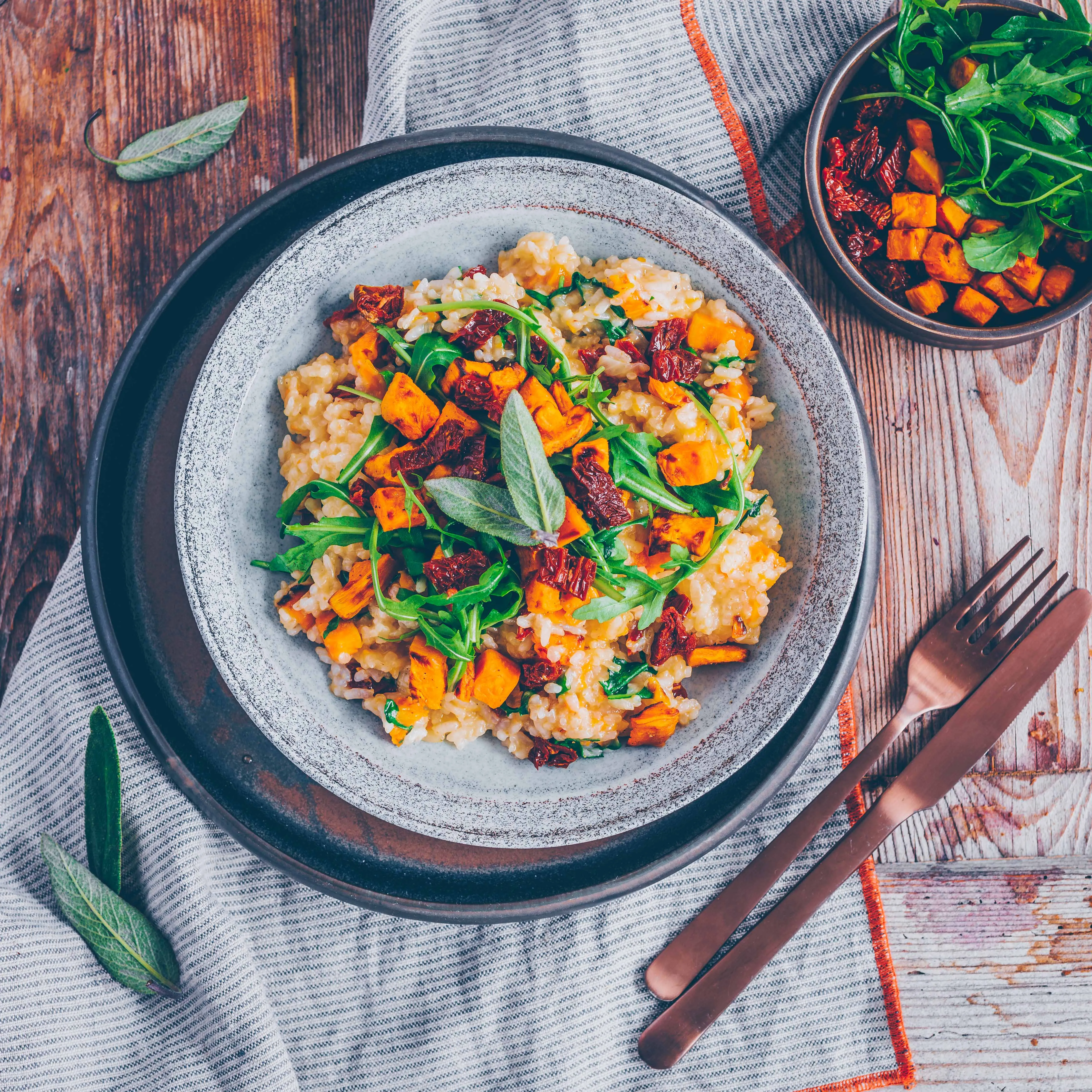 Portion Süßkartoffel-Risotto mit frischem Rucola und veganem Parmesan bestreut