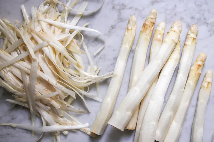 Professionelles Schälen von weißem Spargel und Entfernen der holzigen Enden, ein wichtiger Schritt für jedes Spargelrezept.