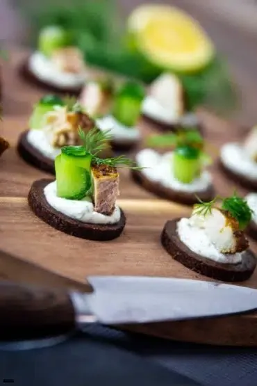 Pumpernickeltaler mit frischer Gurke, Dill und Räucherfisch als Vorspeise.