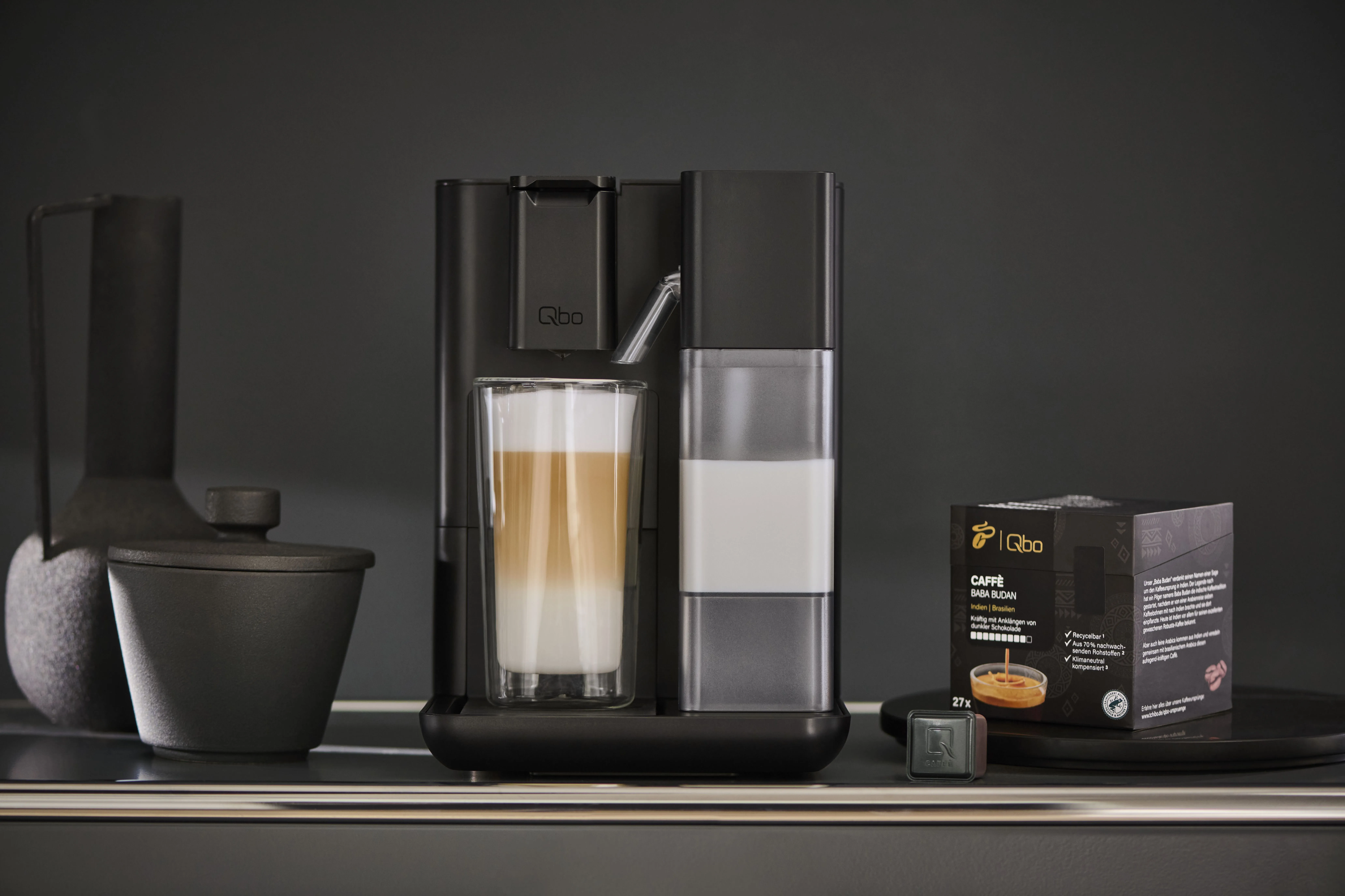 Qbo Milk Master Velvet Black mit frisch gebrühtem Vanille-Espresso und aromatischen Vanilleschoten, symbolisierend exzellenten Qbo Kaffee.