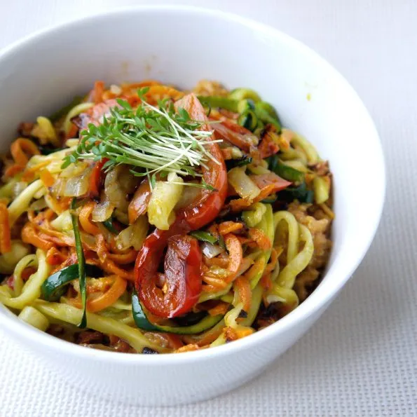 Quinoa-Gemüse-Bowl mit Zoodles aus Zucchini und Karotten, frischer Kresse und einer Prise Kurkuma, reich an Eiweiß