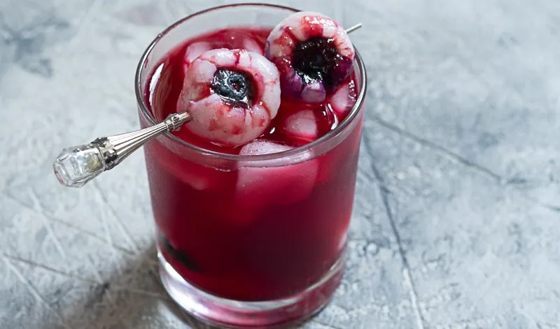 Realistisch aussehende Litschi-Augäpfel mit Blaubeeren als gruselige Dekoration für Halloween Cocktails.