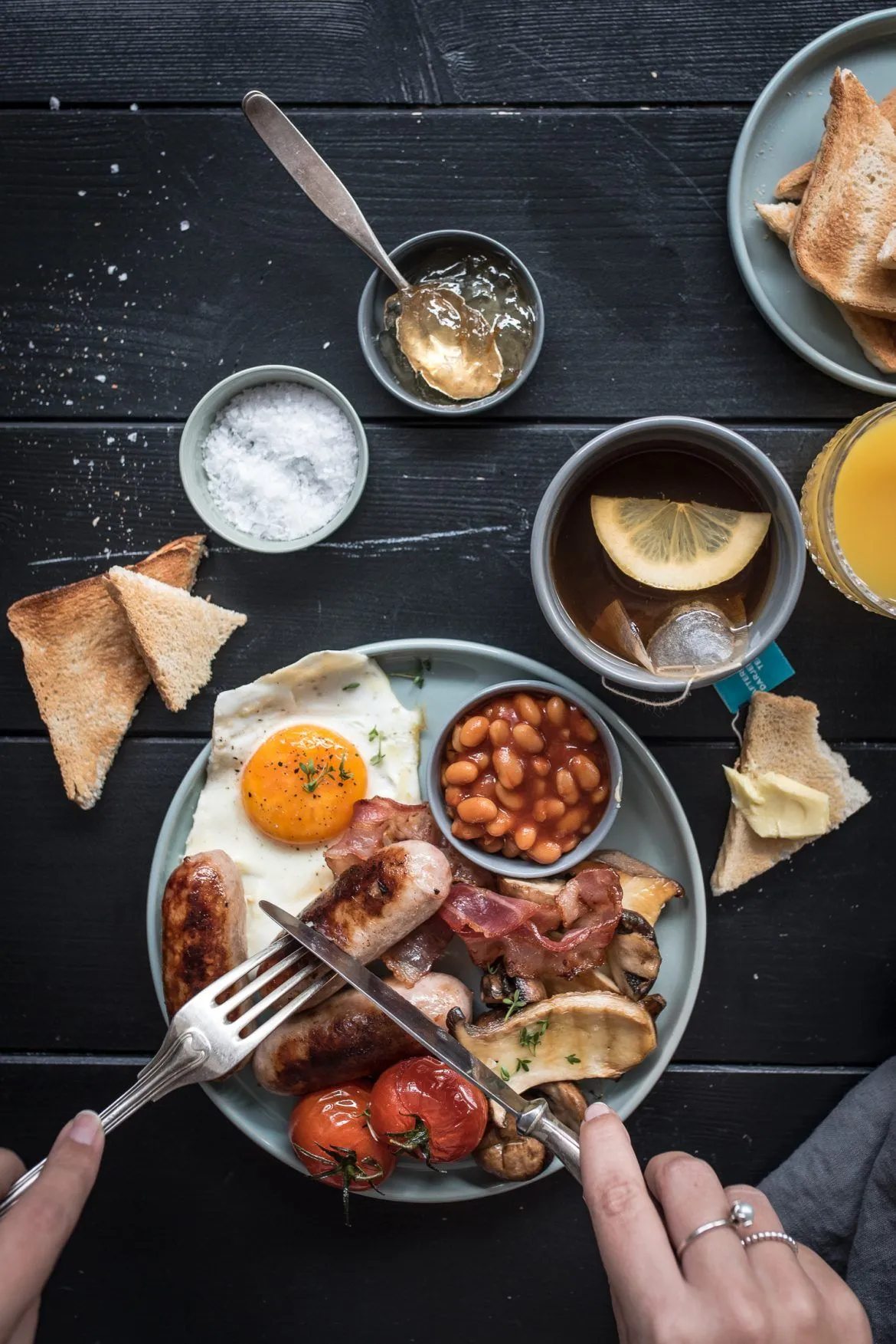 Reichhaltiges Full English Breakfast mit Spiegeleiern, Speck, Würstchen und Toast