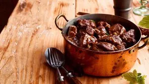 Reichhaltiges Wildgulasch schmort langsam in einem gusseisernen Topf, um die Aromen zu entfalten.