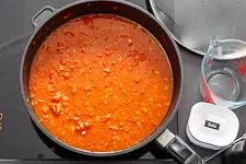 Reis, Ajvar, Tomatenmark und Gemüsebrühe werden in der Pfanne vermengt