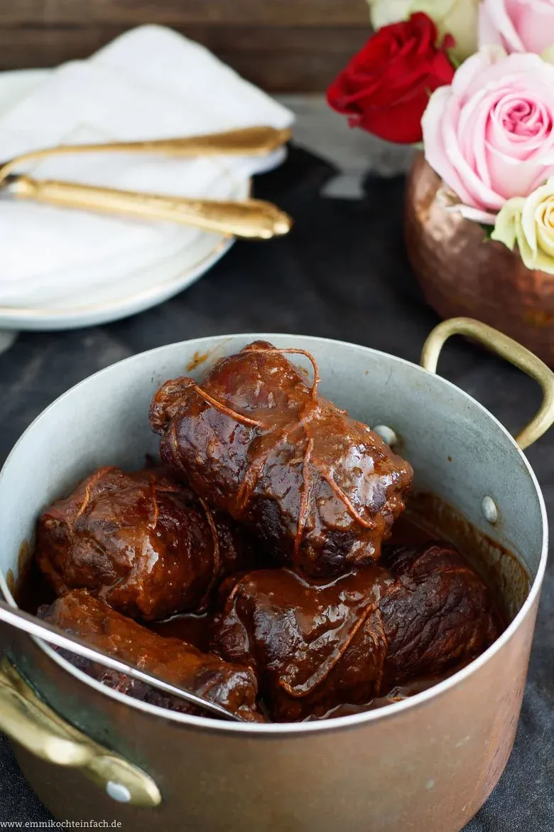 Rinderroulade auf einem Teller mit Kartoffelknödeln und Rotkohl, angerichtet für ein traditionelles deutsches Festmahl.