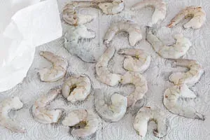 Roh, geschälte und aufgetaute Garnelen abwaschen und trocken tupfen – der erste Schritt für einfache Garnelen Rezepte