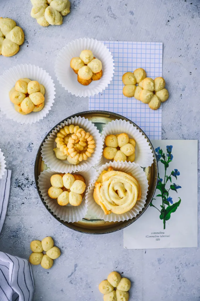Rohe Butterkekse in verschiedenen Formen, frisch auf ein Backblech gespritzt, bereit zum Backen. Tipp für ein einfaches Butterkekse Rezept.