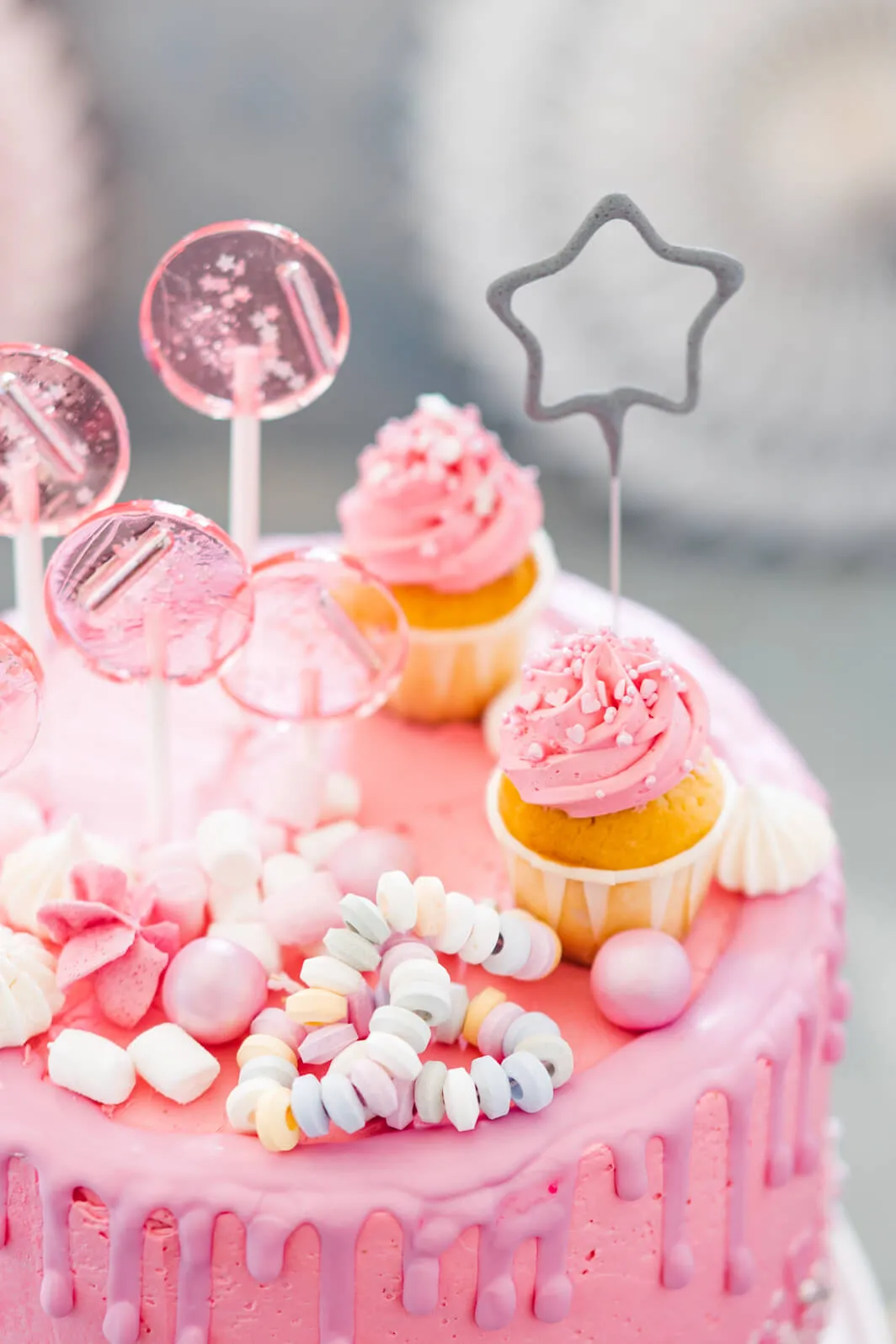 Rosa Geburtstagskuchen, verziert mit süßen Lollies und Streuseln, bereit für die Feier