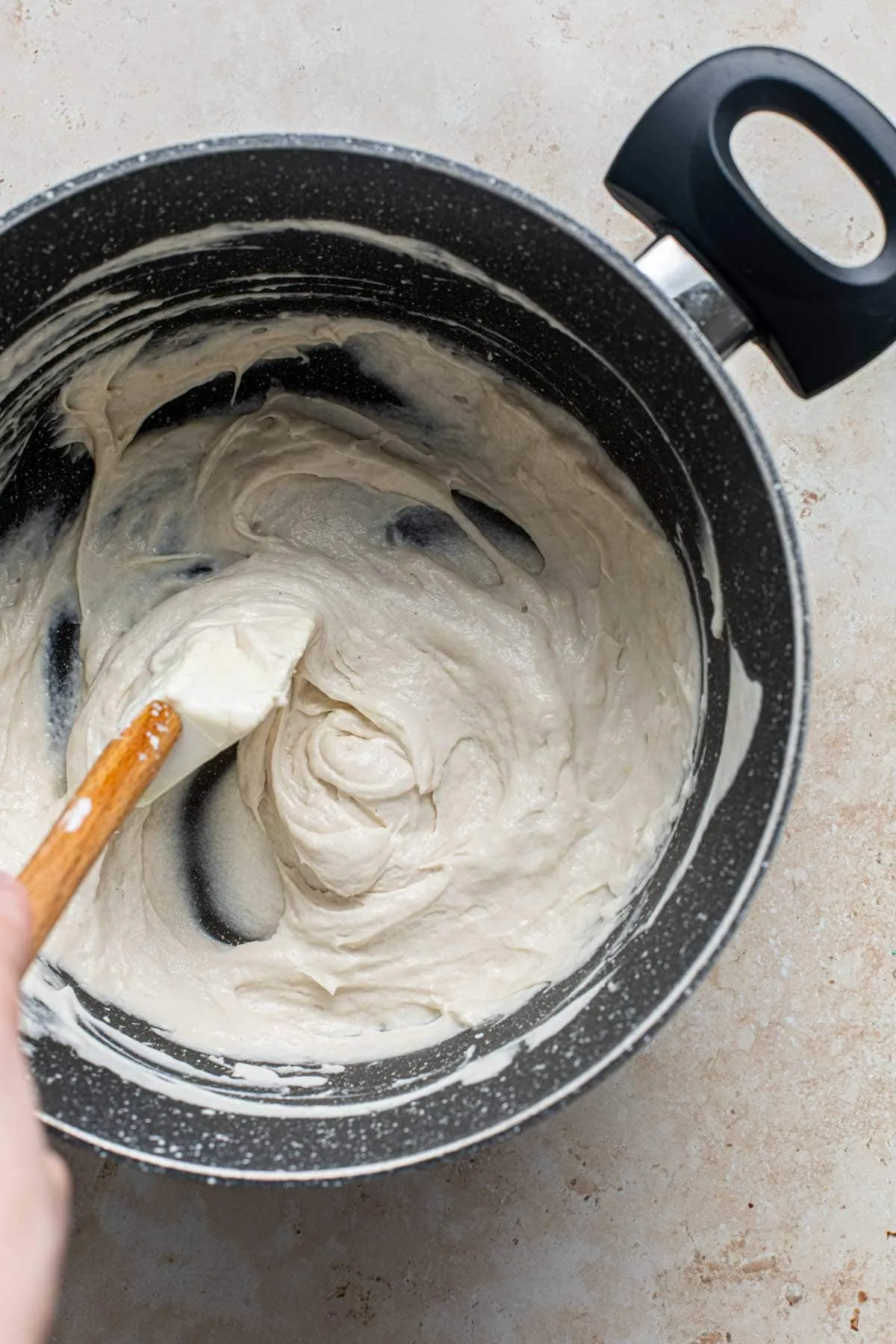 Rühren der Cashew-Käsemasse in einem großen Topf zur Vorbereitung der Lagerung