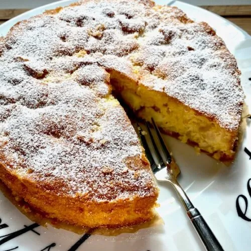 Saftiger Apfelkuchen mit Puderzucker auf einer Tortenplatte