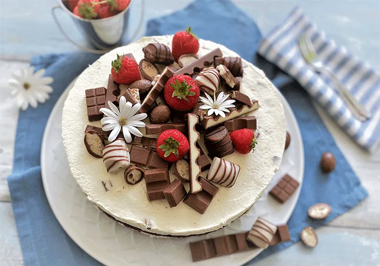 Saftiger Geburtstagskuchen mit Kinderschokolade, frischen Erdbeeren und cremiger Mascarpone-Füllung, verziert mit Kinderriegeln und Schoko-Bons.