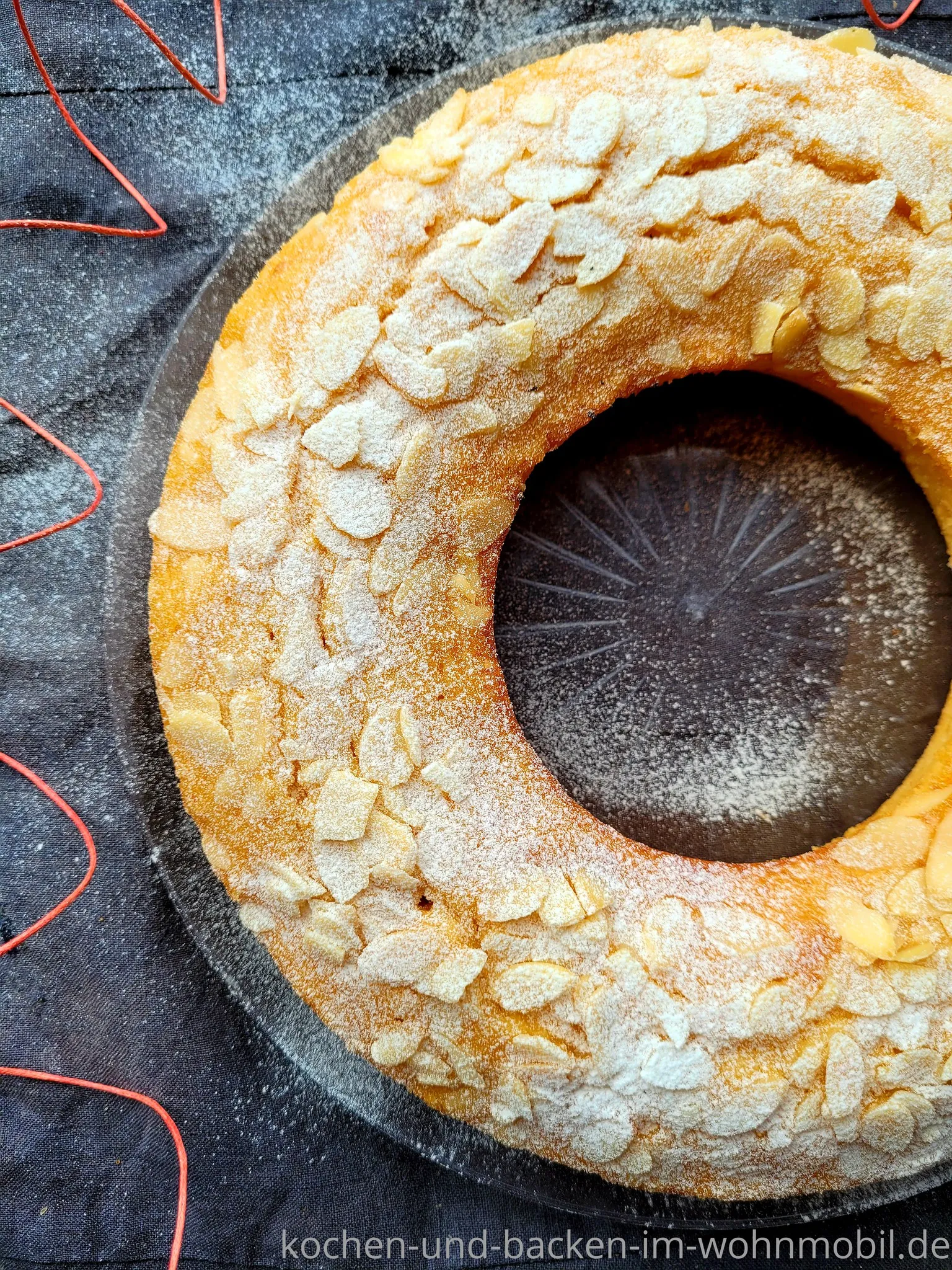 Saftiger Marzipankuchen mit knusprigen Mandelblättchen, frisch gebacken im OMNIA Camping Backofen.