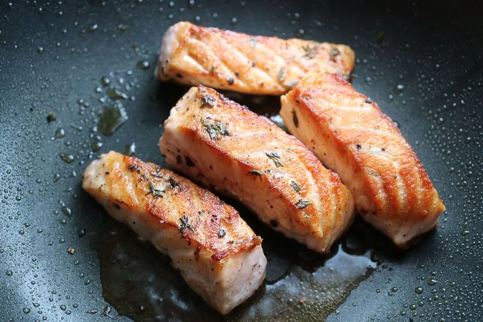 Saftiges Lachsfilet wird in einer Pfanne angebraten, ein schneller Schritt für Lachsrezepte zum Abnehmen