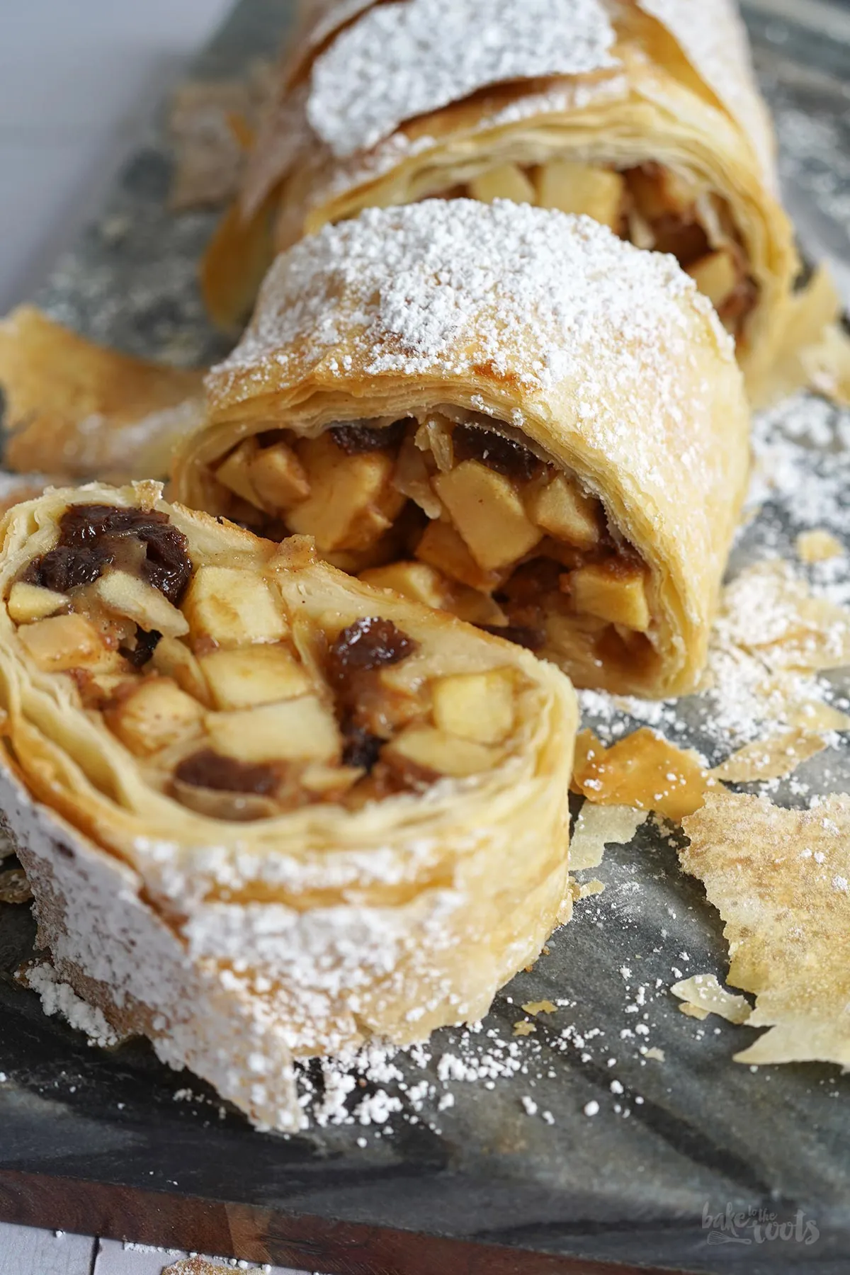 Scheiben von frisch gebackenem Apfelstrudel mit goldbraunem Filoteig und reichhaltiger Apfelfüllung, bereit zum Servieren.