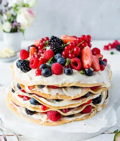 Schichtkuchen aus Pfannkuchen mit Beeren und einer hellen Creme
