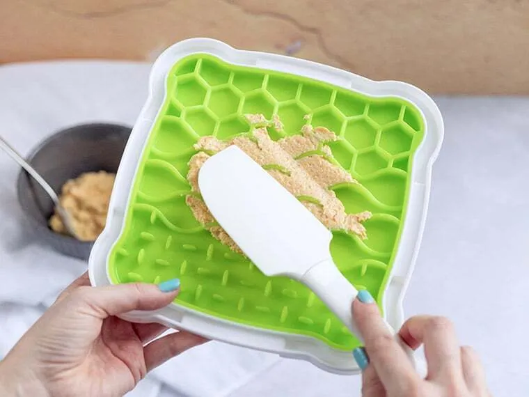 Schleckmatte wird mit einem Spachtel befüllt