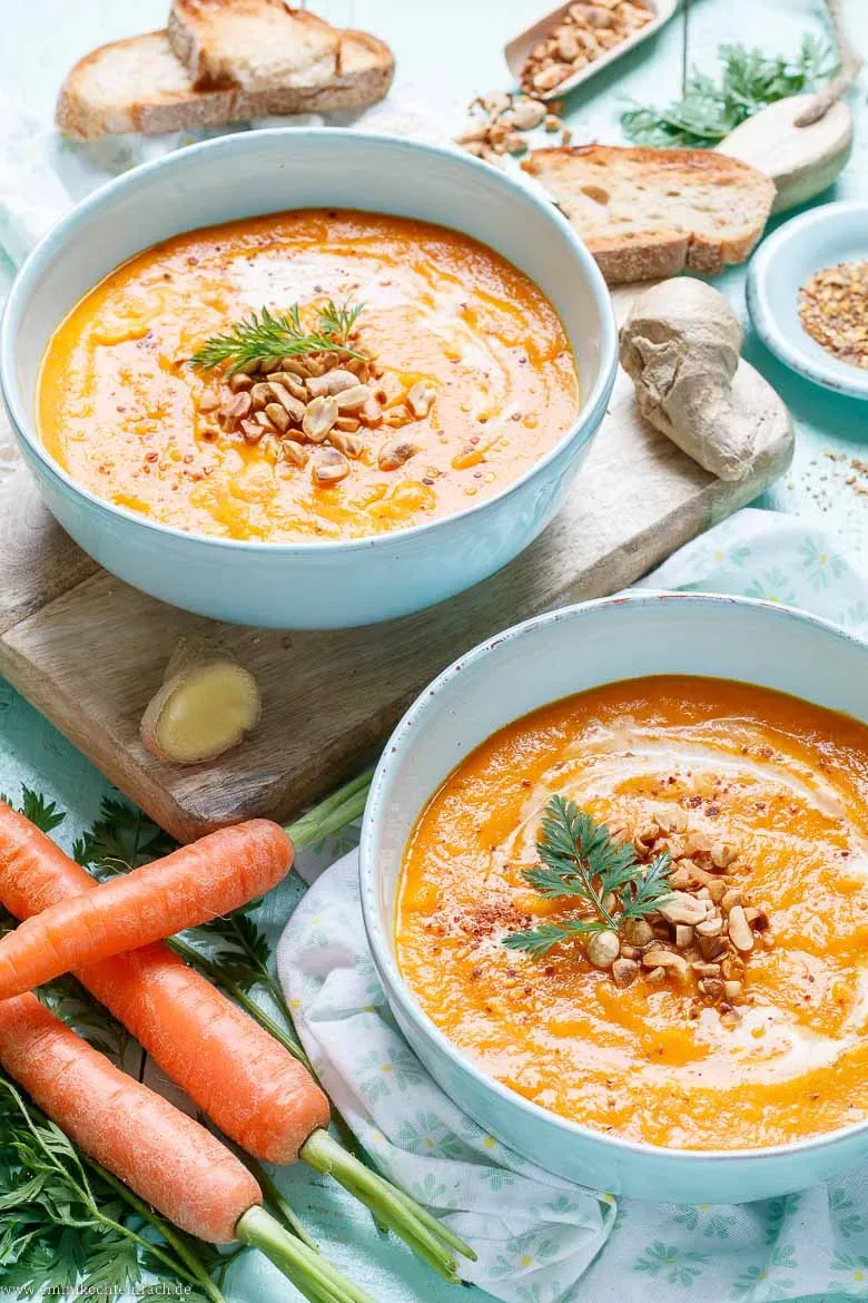 Schnelle Karotten Ingwer Suppe im Topf mit frischen Karotten und Ingwer daneben