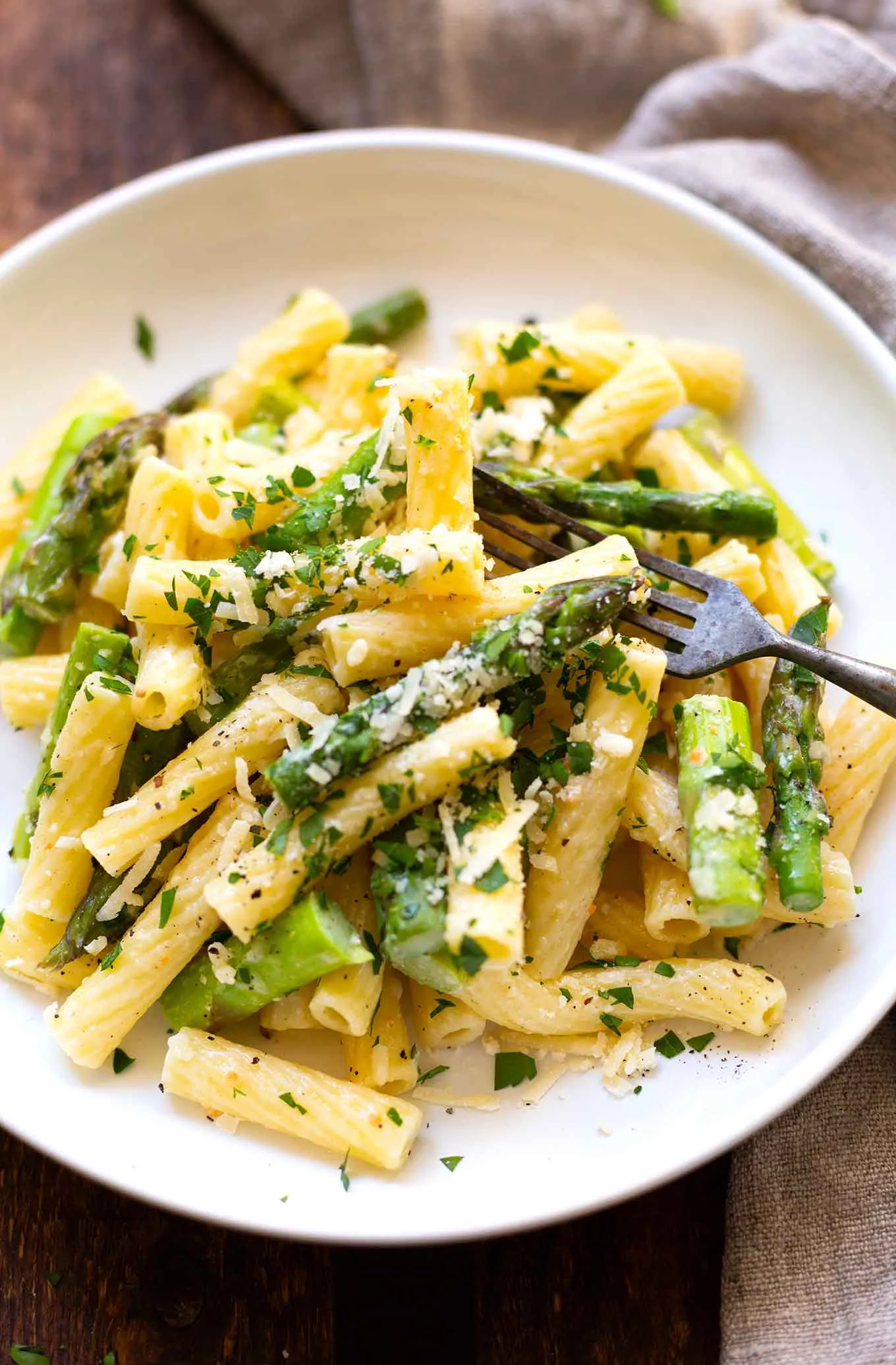 Schüssel mit fertig zubereiteter Pasta mit grünem Spargel und Parmesan, garniert mit frischer Petersilie, schnelle Rezepte mit grünem Spargel