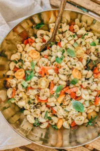 Schüssel mit vegetarischem Nudelsalat, der mit Olivenöl beträufelt wird