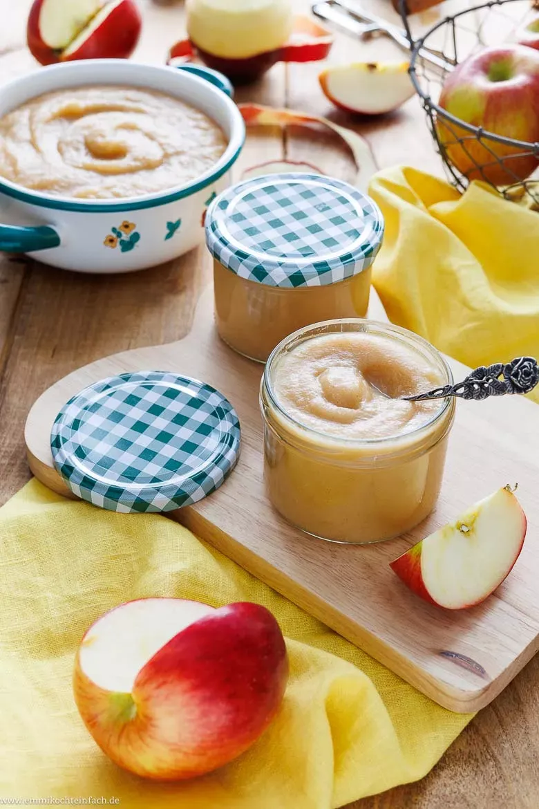 Selbstgemachtes Apfelmus in sterilen Schraubgläsern zur Konservierung, auf einem Holztisch
