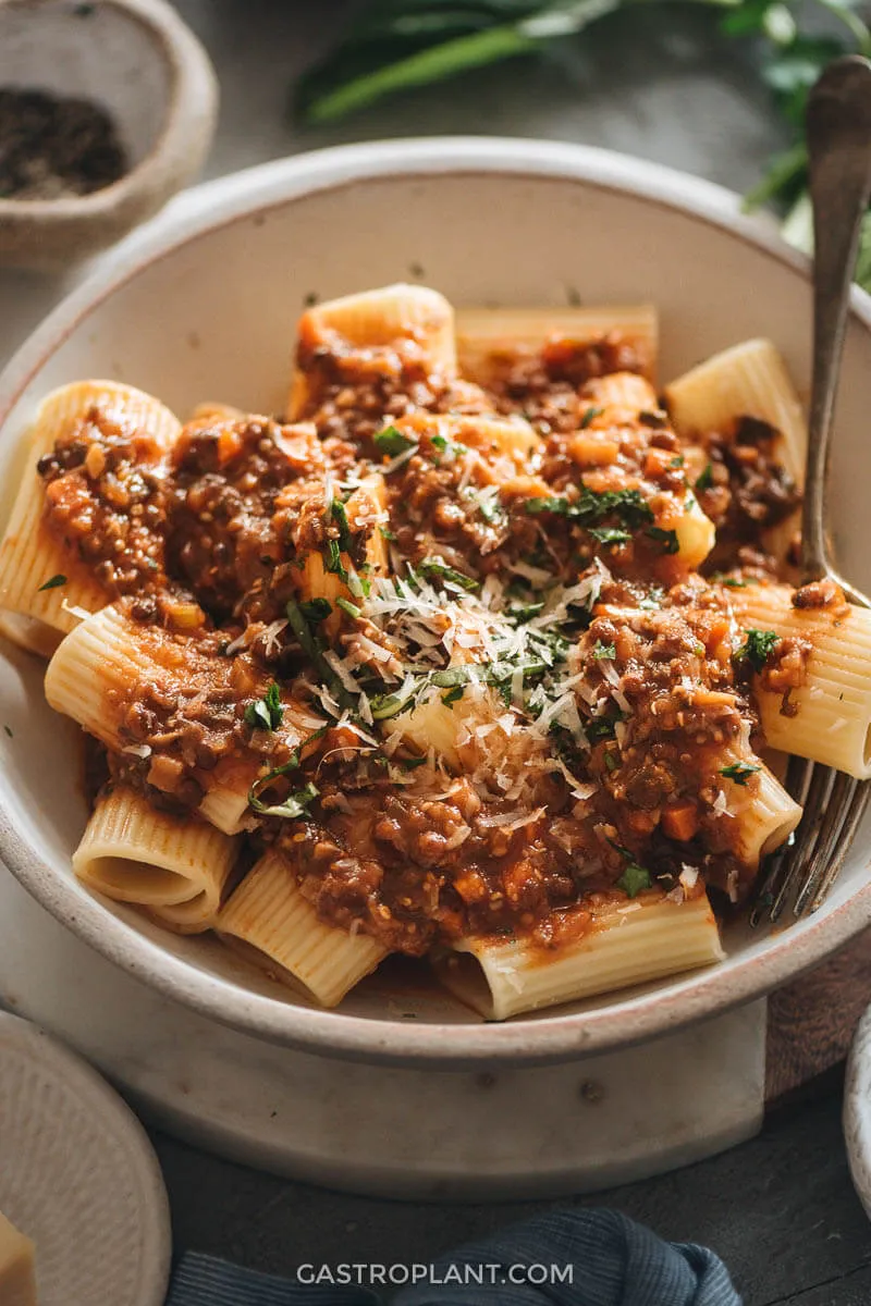 Servierfertige vegane Bolognese auf Vollkornpasta mit Basilikum