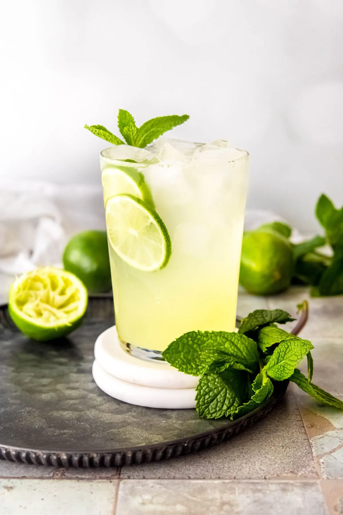 Serviertablett mit hausgemachtem Cool Lime Refresher, frischer Minze und Limettenhälften.