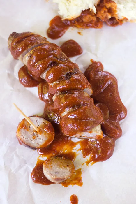 Servierte Currywurst mit knusprigen Pommes und einem Brötchen