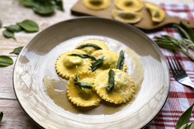Servierte Spinat-Ricotta-Ravioli in Salbeibutter, bestreut mit Parmesan