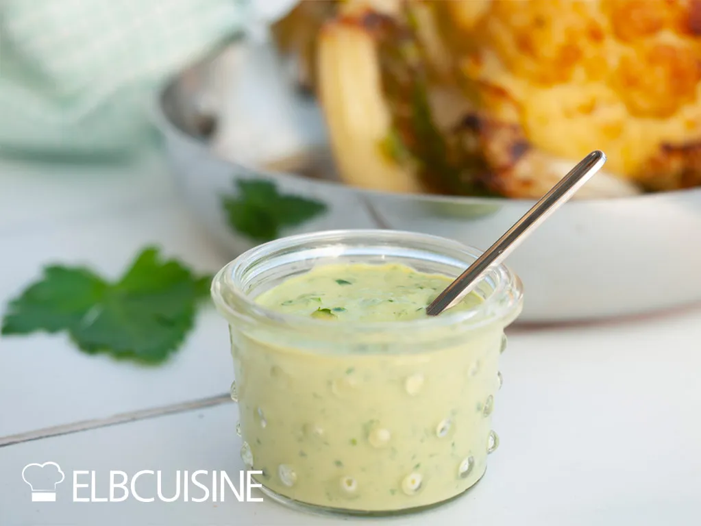 Servierter gerösteter Ottolenghi Blumenkohl mit der charakteristischen grünen Tahini-Sauce und frischer Petersilie