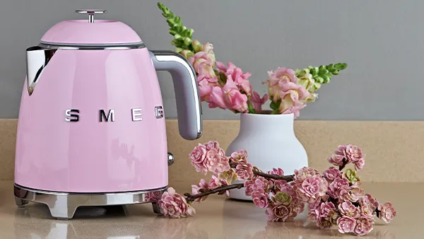 SMEG Wasserkocher in Cadillac Pink neben rosa Blumen