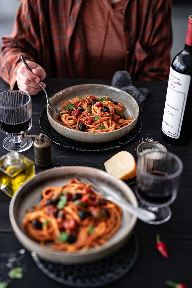 Spaghetti alla Puttanesca in einer Pfanne mit Tomaten und Oliven