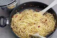 Spaghetti werden in der Pfanne mit dem Speckfett vermischt