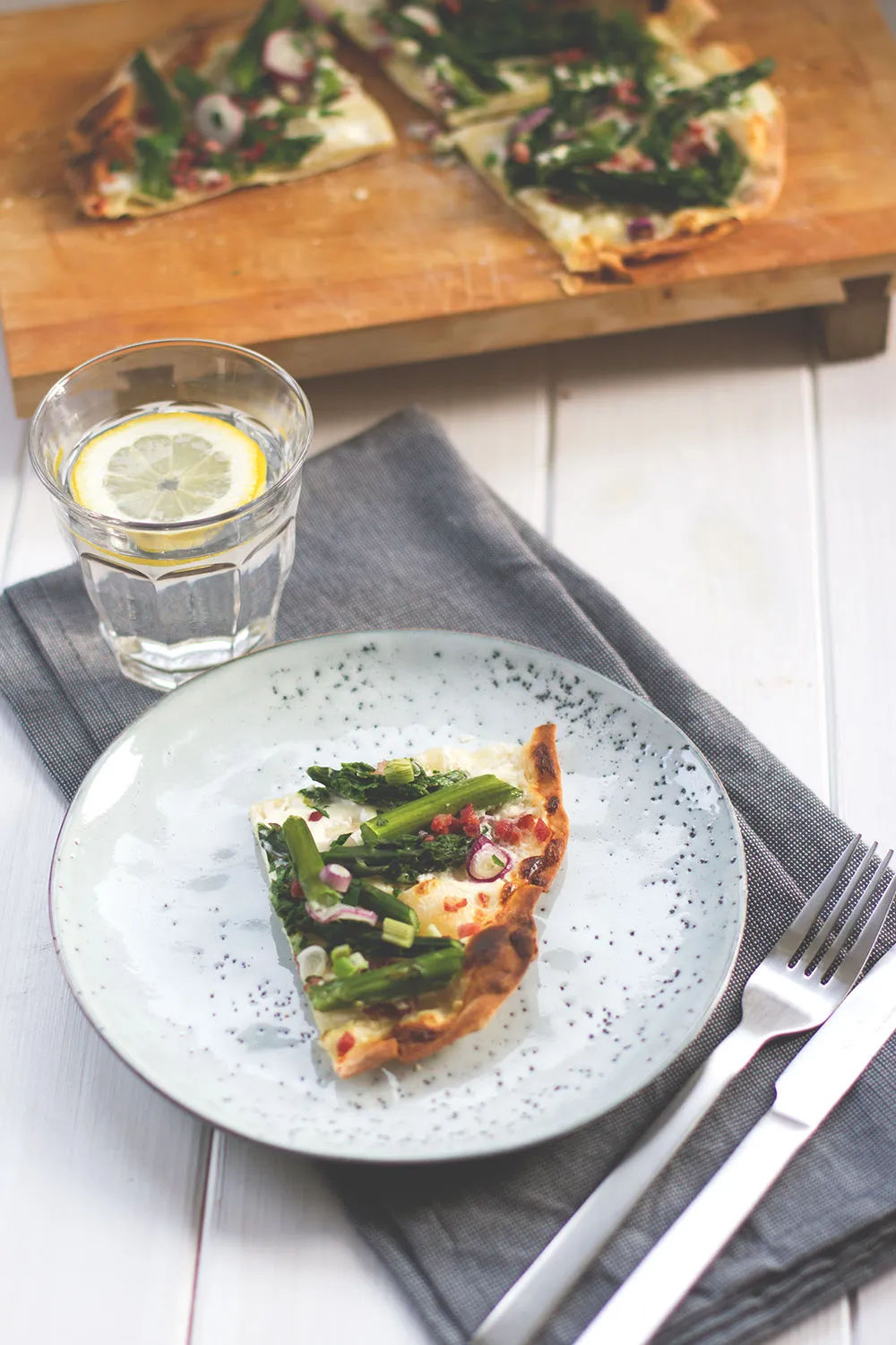 Spargel-Mascarpone-Flammkuchen wird mit Pizzaschneider in Stücke geteilt