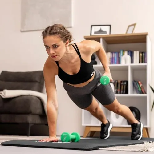 Sportliche Frau führt eine Plank mit grüner Hop-Sport Hantel in einer Hand aus