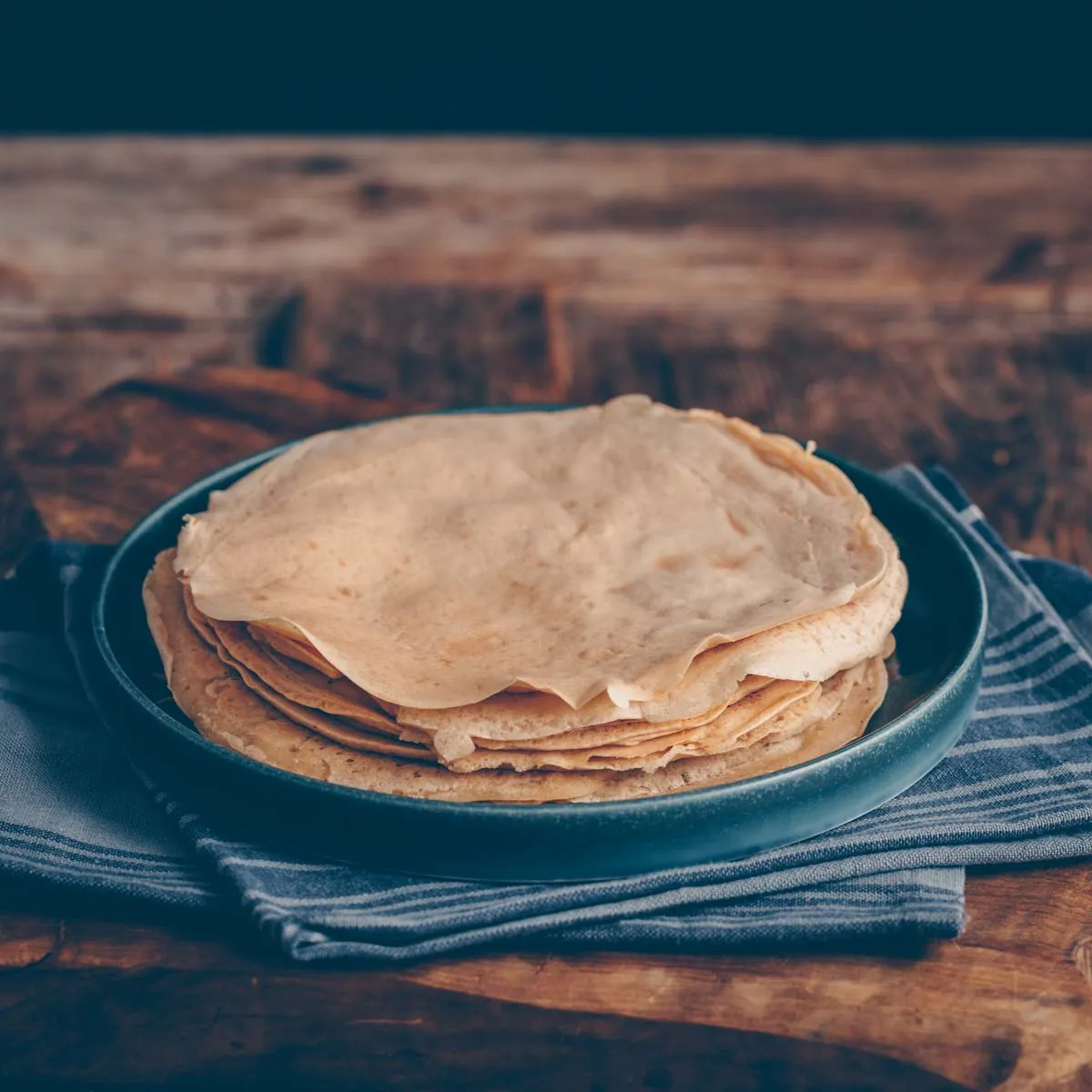 Stapel von goldbraunen Crêpes auf einem Teller, perfekt gebacken für das ideale Crêpe Rezept.