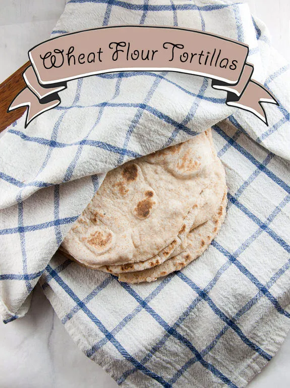 Stapel von selbstgemachten Weizenmehl-Tortillas in einem sauberen Küchentuch eingewickelt