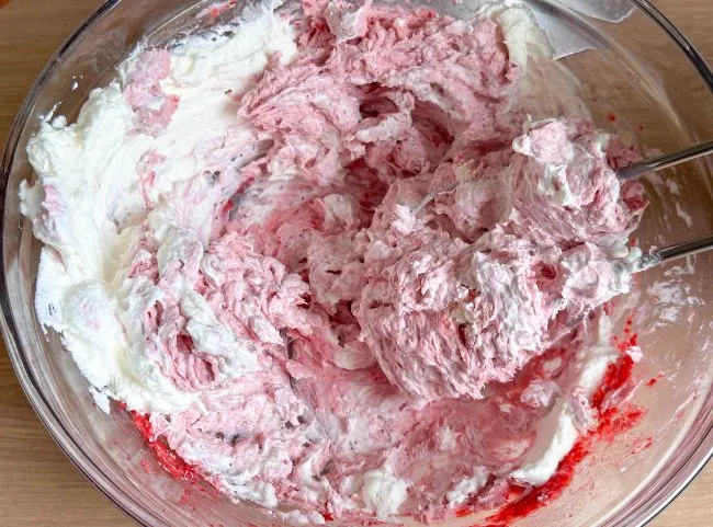 Steif geschlagene Sahne wird vorsichtig unter die Tortencreme gehoben