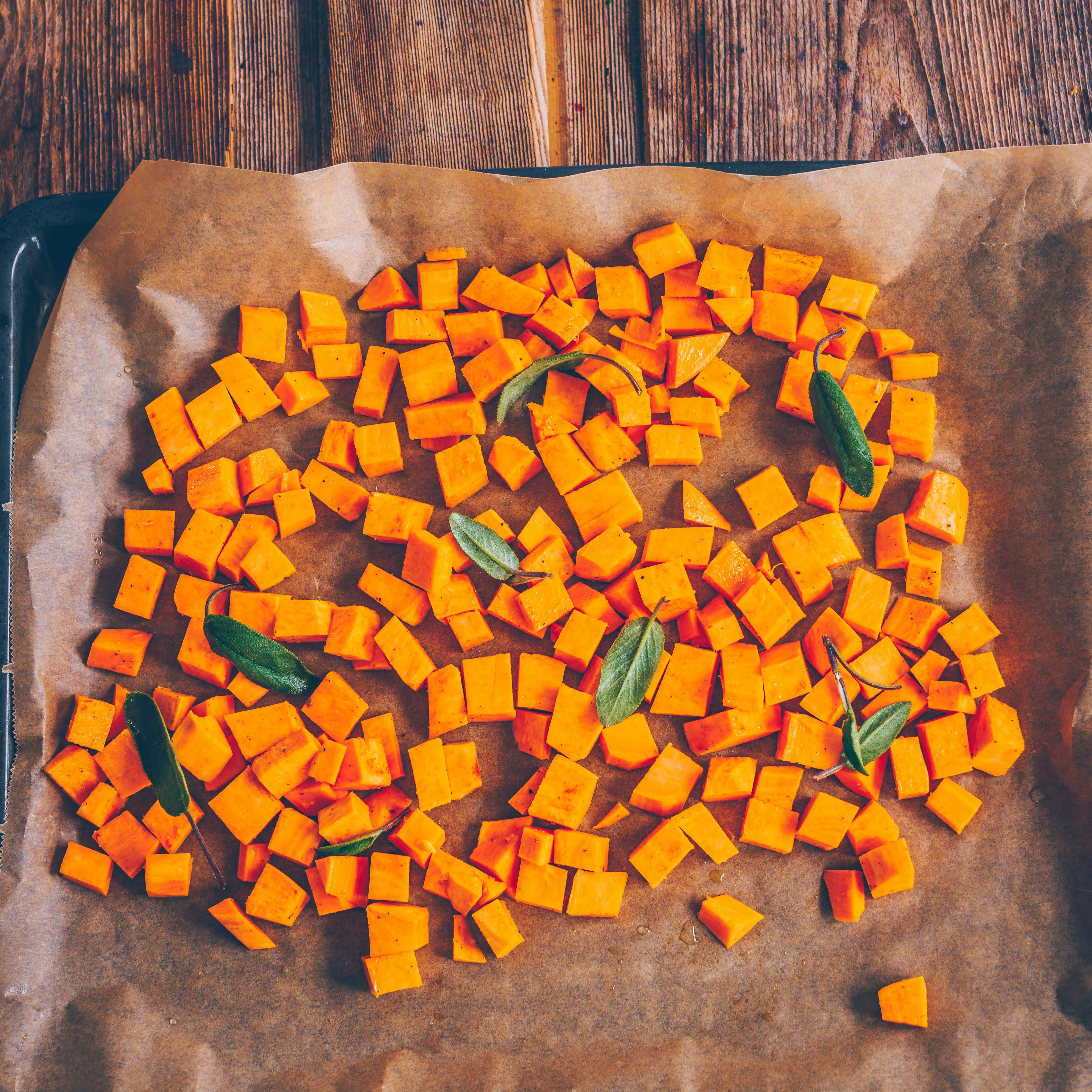 Süßkartoffelwürfel mit Salbei und Olivenöl auf Backblech