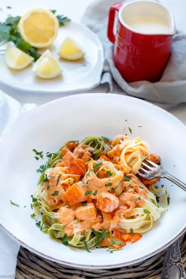 Tagliatelle mit Lachs und cremiger Sahnesoße, fertig angerichtet auf einem Teller