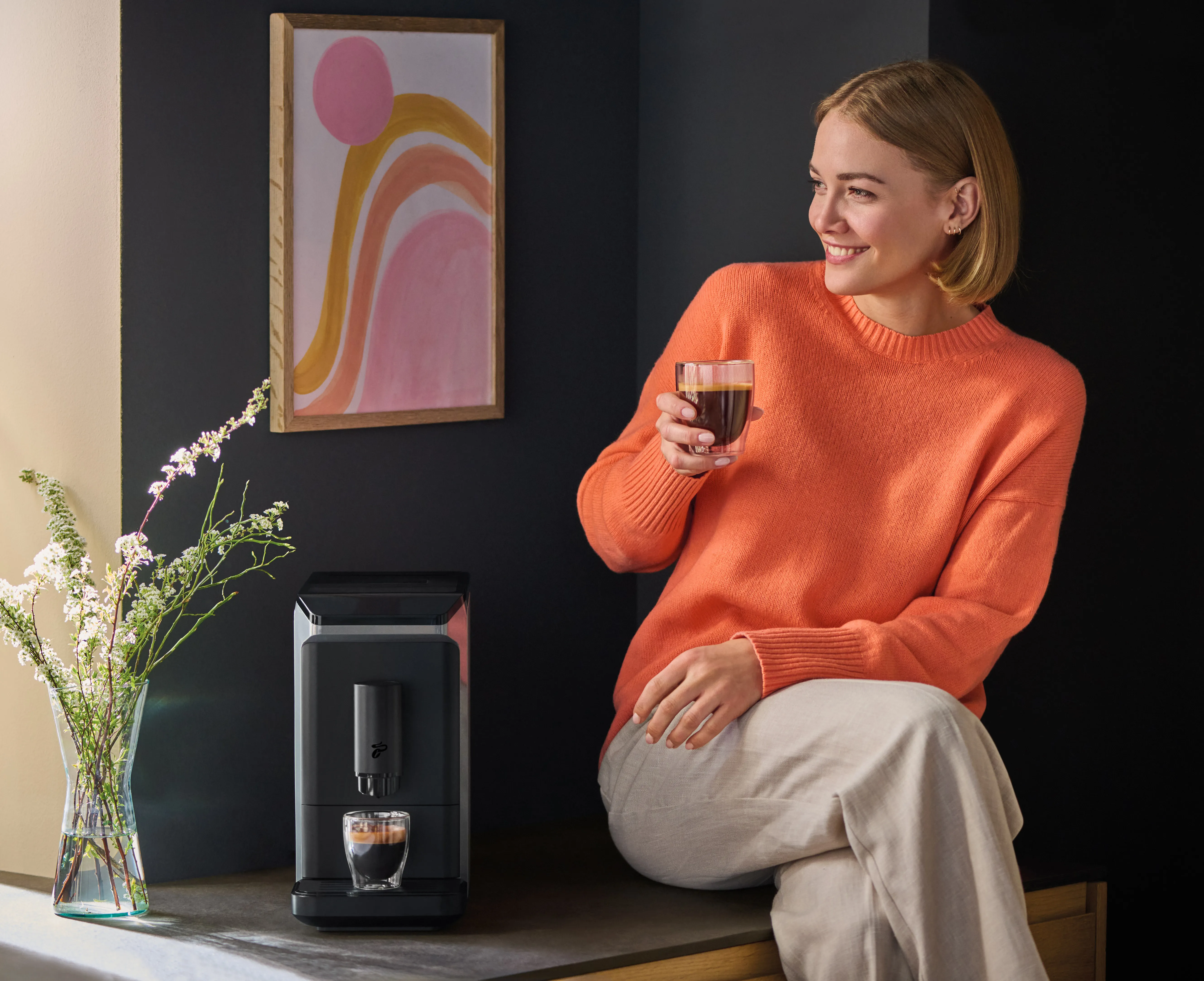 Tchibo Esperto mini Kaffeevollautomat in Grau mit Kaffeetasse, präsentiert als der kleinste Vollautomat.