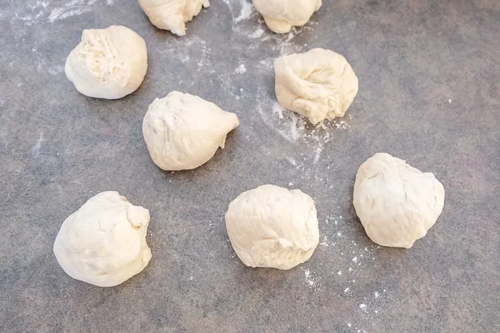 Teig für Brötchen, in kleine Stücke gerissen, auf einer Arbeitsfläche
